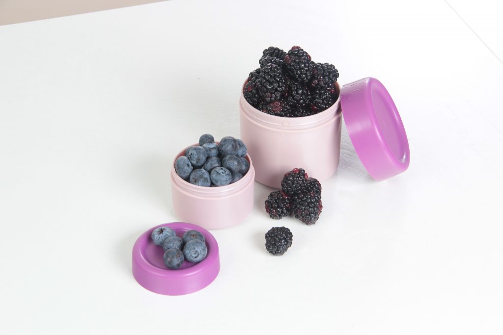 Hilo, lunch box series indludes small round boxes, ideal for small pieces of fruits and snacks you do not want to be mixed with primary lunch. Pink boxes are on the tabletop.