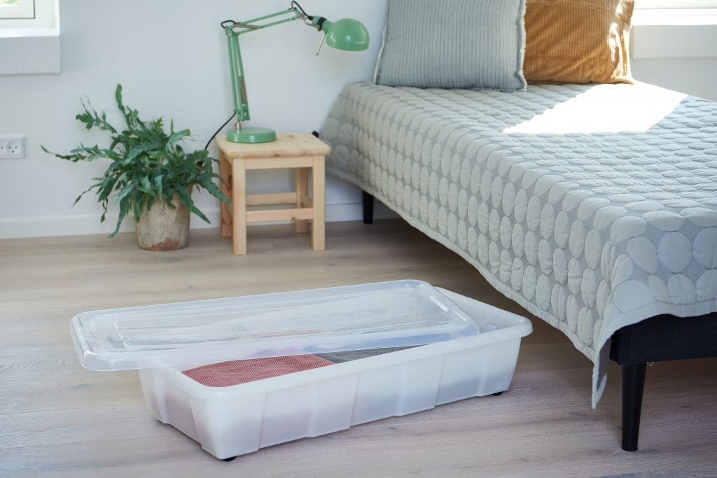 Bedroller Easy is a perfect under bed storage due to wheels and low profile connected with clip-on lid and semitranslucent material. The container filled with blankets stays near the bed and has a lid opened.