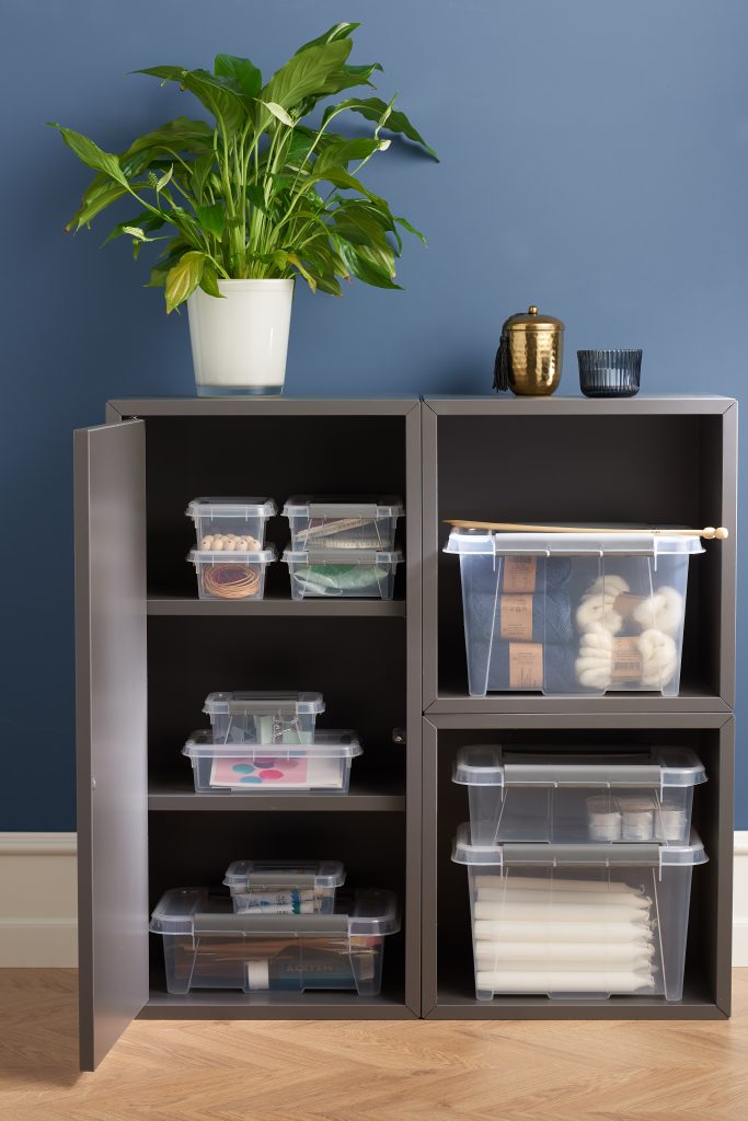 Stackable translucent Probox clip-closed storage boxes in four different sizes, with QR codes to organize storage. Boxes are placed inside a cupboard and used to store crafting household items.