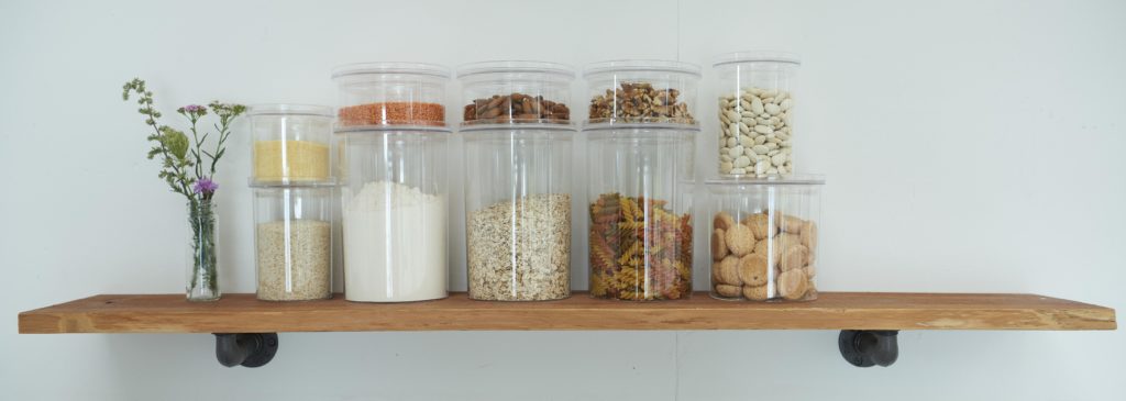 Plastikowe pojemniki do przechowywania żywności na otwartej półce w kuchni